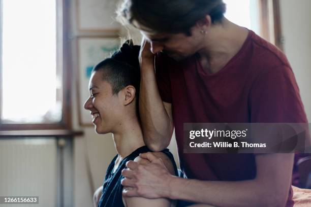 man giving girlfriend sports massage at home - massage couple stock pictures, royalty-free photos & images