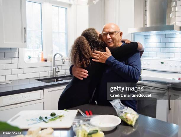 tender moment between grandfather and teenage granddaughter in kitchen. - sandwich generation stock pictures, royalty-free photos & images