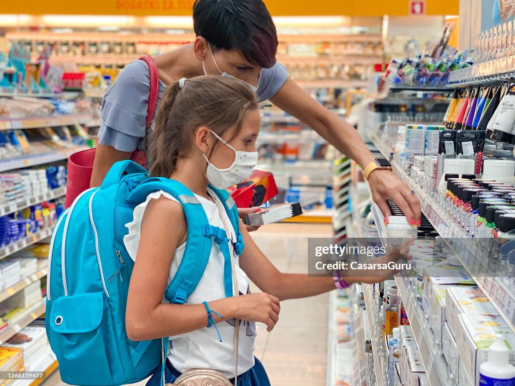 Mother and Daughter in Protective Face Mask Back To School Shopping During COVID-19 Pandemic - stock photo