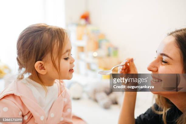 mother giving medicine to little girl - caucasian woman sick in bed coughing stock pictures, royalty-free photos & images