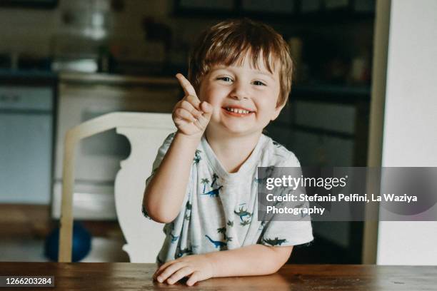 portrait of a smiling toddler while raising his index finger - two boys talking stock-fotos und bilder