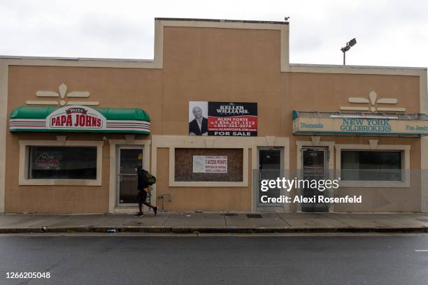 Man wearing a mask walks past a Papa Johns pizza next to a for sale sign as the state of New Jersey continues Stage 2 of re-opening following...