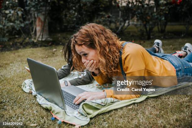 mother and daughter using laptop and tablet together outdoors - mutter kind lachen zuhause stock-fotos und bilder