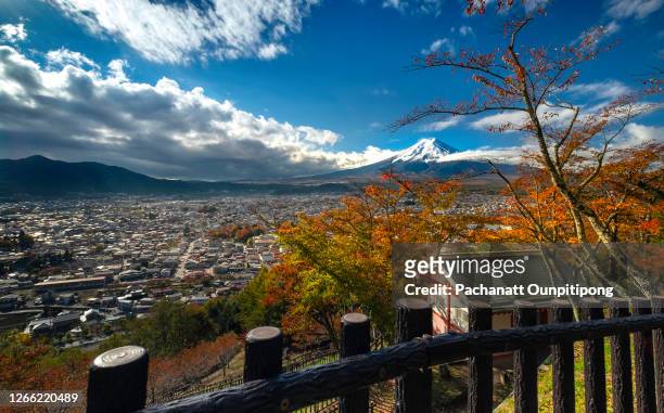 landscape of mt. fuji with view of city with wooden fence at foreground on a blue sky day in autumn season in fujiyoshida, japan - foothills stockfoto's en -beelden