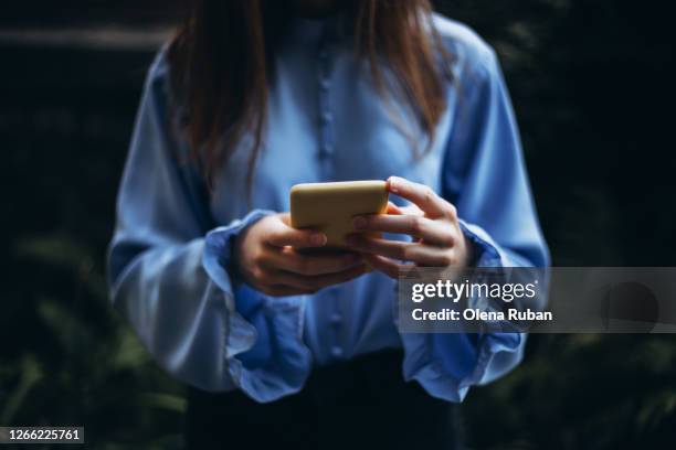 young woman holds a mobile phone in her hands - blue note pad stock pictures, royalty-free photos & images