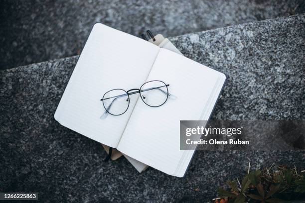 transparent glasses lie on a blank notebook - book top view stockfoto's en -beelden