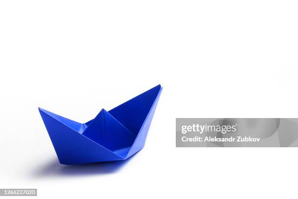 a blue paper boat on a bright white background. copy space - origami boat stock pictures, royalty-free photos & images