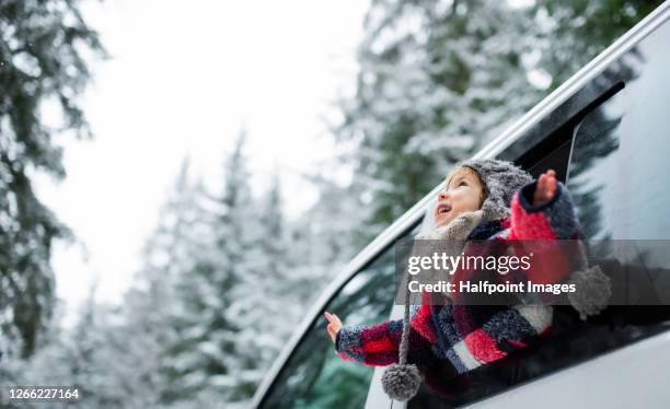 happy small girl looking out through car window in winter nature. - winter car window foto e immagini stock