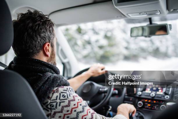 rear view of mature man driving car on snowy road. - christmas driving stockfoto's en -beelden