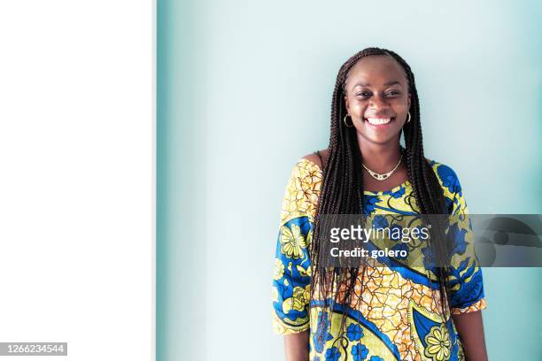 portrait of smiling african woman in front of blue wall - african tradition stock pictures, royalty-free photos & images