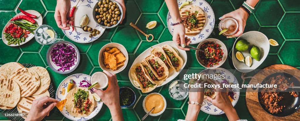 Fiesta de tacos en casa con tortillas, salsa de tomate y manos de la gente
