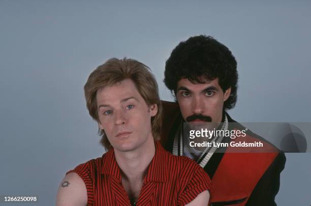 American rock and soul duo Hall & Oates with both dressed in red in a studio portrait, against a grey background, circa 1980.