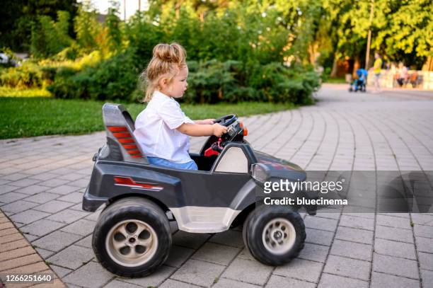 cute baby girl in electric toy car - toy car stock pictures, royalty-free photos & images