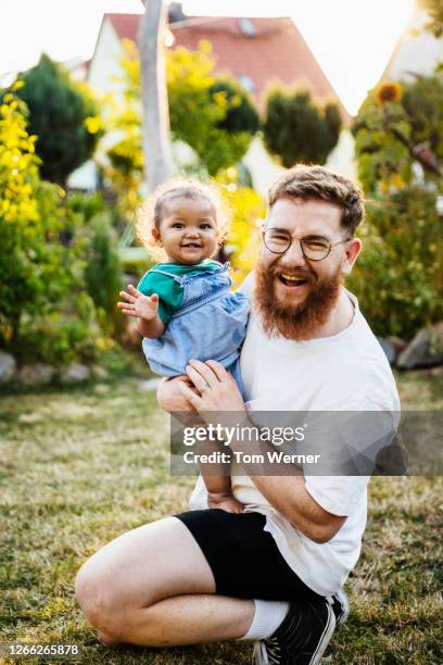 portrait of father with young daughter in garden smiling - baby beard stock-fotos und bilder