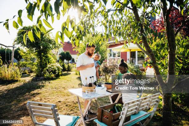 family hanging out around table in garden together - garden furniture stockfoto's en -beelden