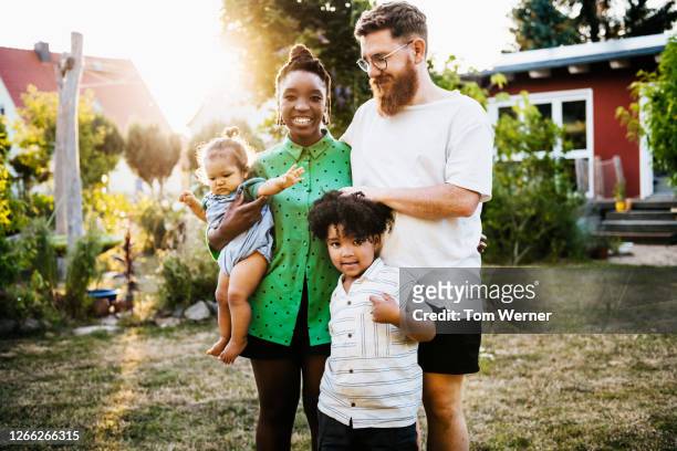 portrait of mixed race couple outdoors with children - multikulturelle gruppe stock-fotos und bilder