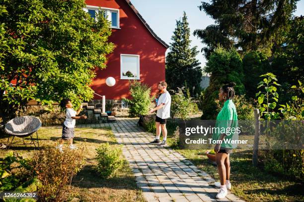 family of three playing with ball in back garden - german film ball stock-fotos und bilder