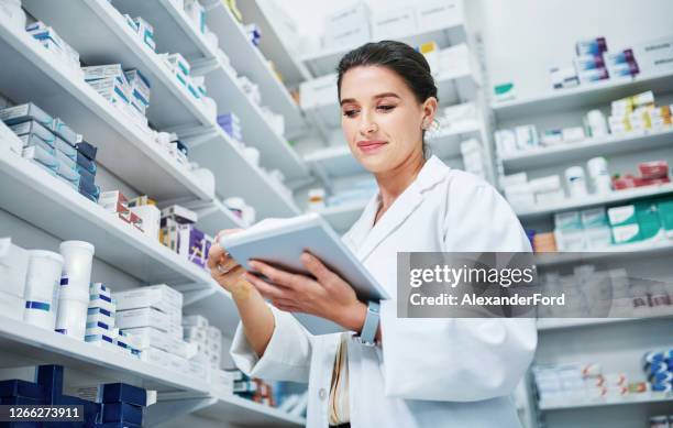 drug dispensing gone digital - female pharmacist with a digital tablet imagens e fotografias de stock