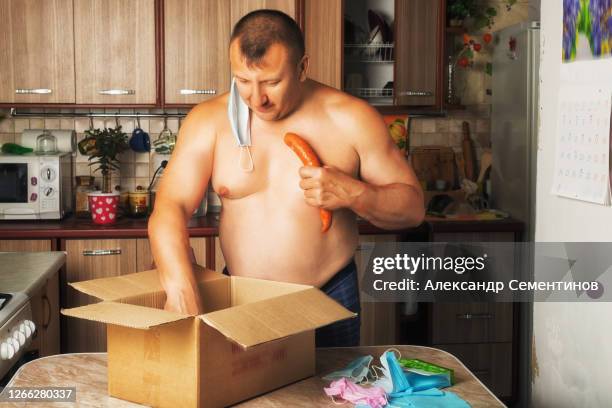 man takes out of the box sausage and canned food. isolation, animal instincts of self-preservation. hunger. - surprise gift stockfoto's en -beelden