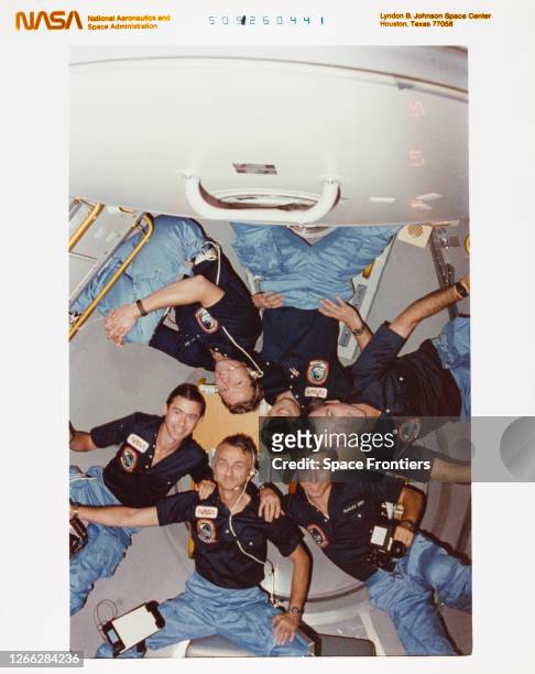 The crew of NASA's STS-9 mission pose in the aft end cone of Spacelab 1 on the Space Shuttle Columbia in Earth orbit, 1983. Clockwise from bottom,...
