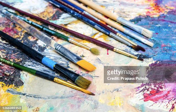 artistic paintbrushes and palette knifes on an old wooden palette - easel imagens e fotografias de stock
