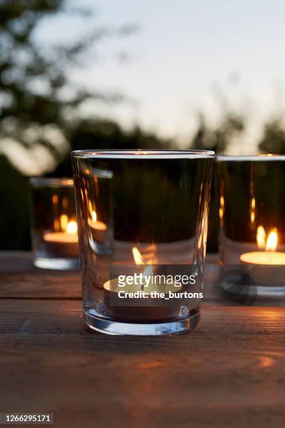 lit tea light candles in glasses on table in garden during sunset - värmeljus bildbanksfoton och bilder