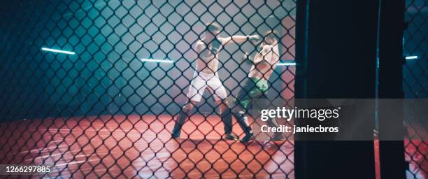 mma fighters throwing punches in octagon. knockout - octagon box stock pictures, royalty-free photos & images
