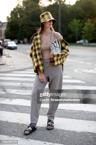 Influencer Jacqueline Zelwis, wearing a yellow black checked jacket and hat by Baum und Pferdegarten, a crop top by Zara, grey pants by Inwear, a bag...