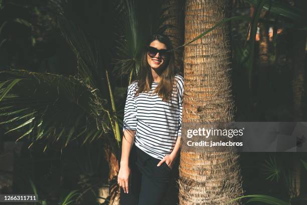 beautiful brunette visiting tropical garden. flirting with camera - date palm tree stock pictures, royalty-free photos & images