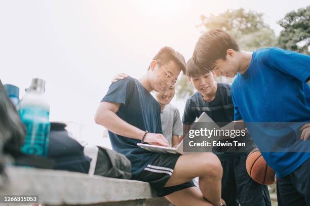 a group of asian chinese teenage boys beside basketball court having discussion and gathering after the game - student athlete stock pictures, royalty-free photos & images