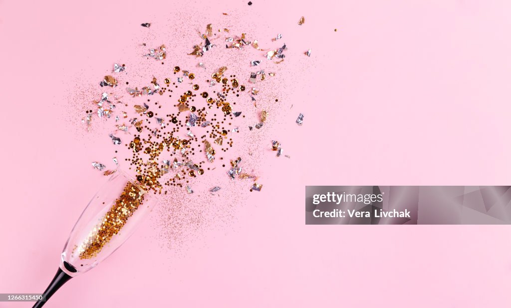 Golden shimmer glitter celebration, christmas and happy new year flat lay with champagne glass on pink background, copy space, top view, vertical