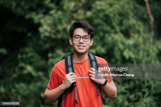 aziatische chinese glimlachende jonge mens die camera in de wildernis bekijkt - chinese people posing for camera stockfoto's en -beelden