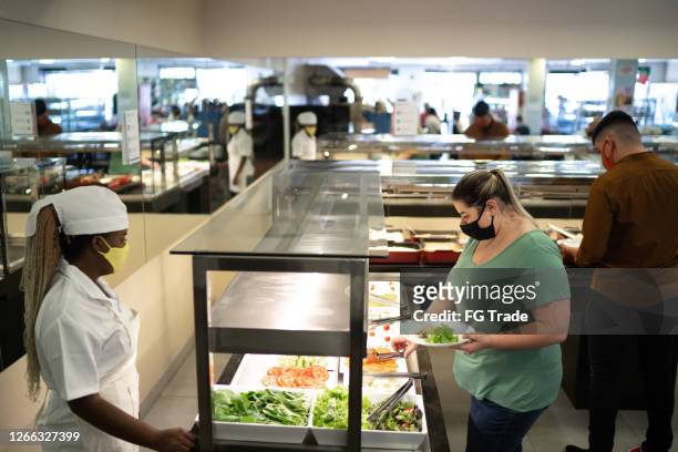customers in a self service restaurant choosing food using face mask - salad bar stock pictures, royalty-free photos & images