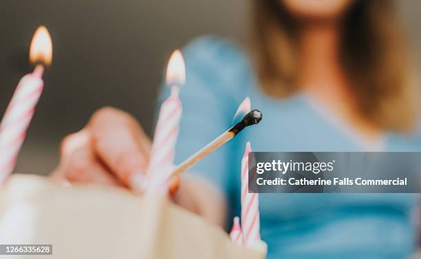 woman lights a birthday candle with a long match - matchstick stock pictures, royalty-free photos & images