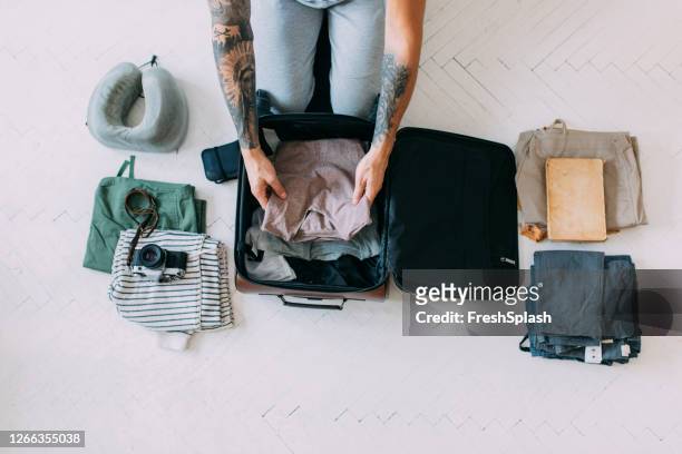 overhead-ansicht eines mannes hände packen kleidung und andere dinge in einen koffer, reisekonzept - packing travel stock-fotos und bilder