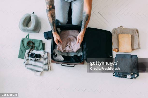 overhead view of a man's hands packing clothes and other things into a suitcase, travel concept - suitcase from above imagens e fotografias de stock