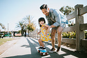 Father Helps Young Daughter Ride Skateboard