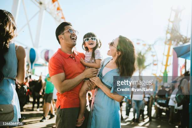 family has fun at outdoor carnival setting - multiracial person stock pictures, royalty-free photos & images