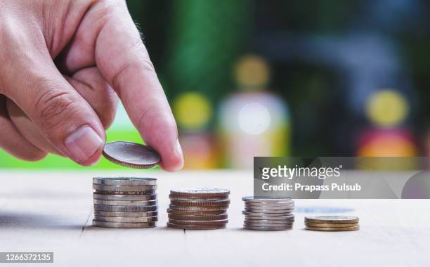 picture of man putting stack of coins into one row - frugality stock pictures, royalty-free photos & images