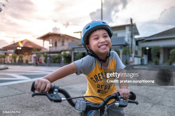 cute smiling boy riding bike - boy thailand stock-fotos und bilder