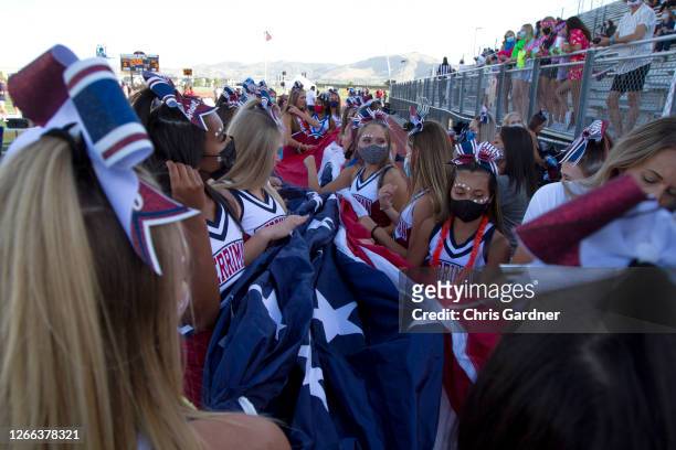 Cheerleaders for the Herriman Mustangs gather a large American Flag for an infield National Anthem ceremony before their game against the Davis Darts...