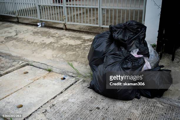 black plastic garbage in front of home - slag heap stock pictures, royalty-free photos & images