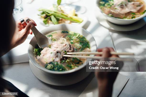 woman eating vietnamese pho soup with noodles and beef - vietnamese food stockfoto's en -beelden