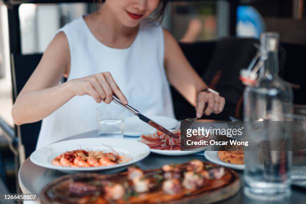 young woman eating spinach food at outdoor restaurant - eating seafood stock pictures, royalty-free photos & images