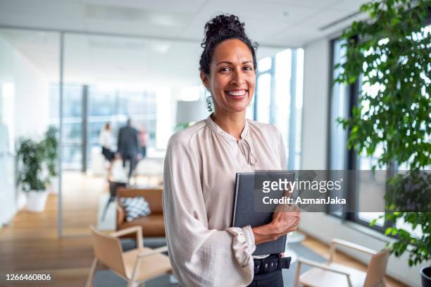 indoor portrait of smiling hispanic businesswoman in office - waist up stock pictures, royalty-free photos & images