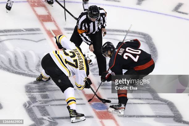 Patrice Bergeron of the Boston Bruins and Sebastian Aho of the Carolina Hurricanes battle for the opening face-off of the first period in Game Three...