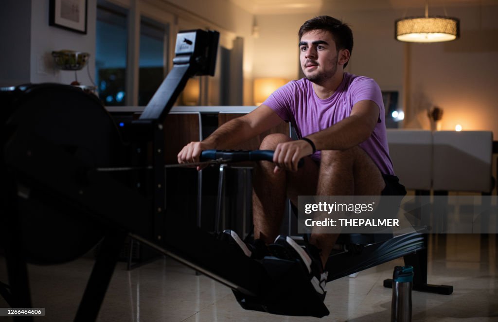 Jovem cubano máquina de remo exercícios na cozinha