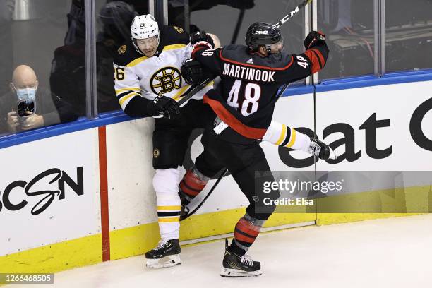 Par Lindholm of the Boston Bruins and Jordan Martinook of the Carolina Hurricanes collide during the first period in Game Three of the Eastern...