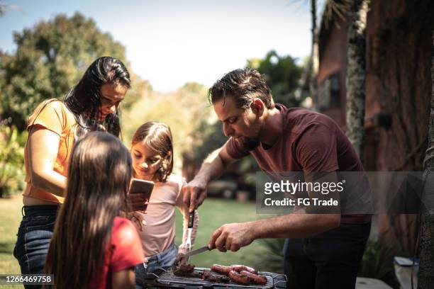 family doing a barbecue together in the backyard - backyard grilling stock pictures, royalty-free photos & images