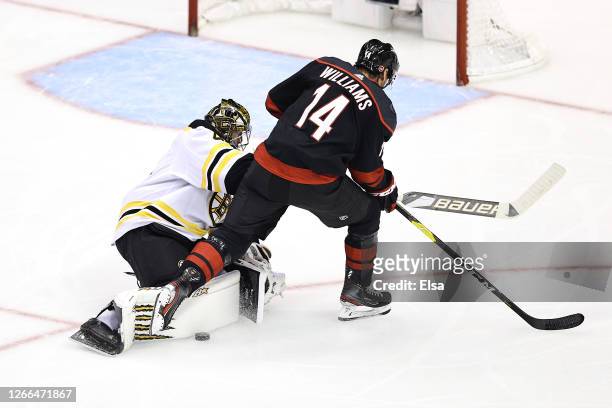 Jaroslav Halak of the Boston Bruins knocks the puck away from Justin Williams of the Carolina Hurricanes during the second period in Game Three of...